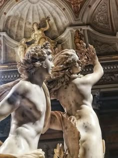 two statues in the middle of a room with an ornate ceiling and walls behind them