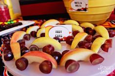 apples and grapes are arranged on a white platter with a sign that says happy kids