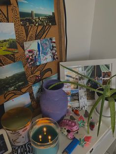 a table topped with pictures and candles next to a plant