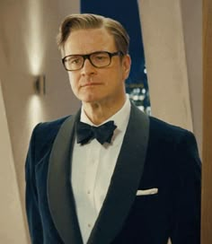 a man in a tuxedo and bow tie is looking at the camera while wearing glasses