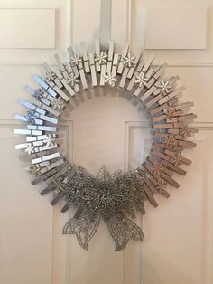 a christmas wreath made out of clothes pins on a white door with snowflakes hanging from it