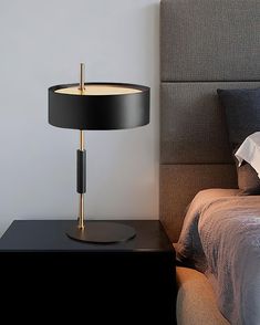 a bed with a black and gold lamp on top of it next to a night stand