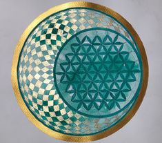 a green and gold plate sitting on top of a white tablecloth covered countertop