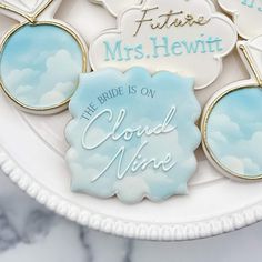 some cookies that are on a plate with the words bride is on cloud nine in blue and white