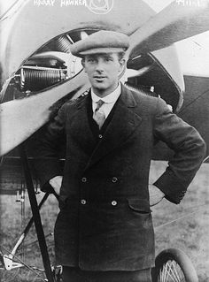 an old photo of a man standing in front of a plane