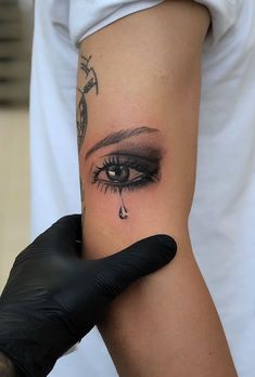 a woman's arm with a tattoo on it and a tear coming out of her eye