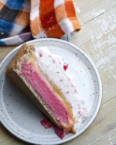 a piece of cake on a white plate with pink, yellow and red frosting