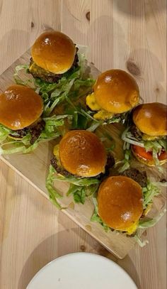 several hamburgers are arranged on a cutting board