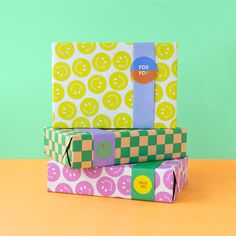 two wrapped presents sitting on top of each other in front of a green and yellow background