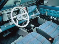 the interior of an old car with blue leather seats and steering wheel, including dash board