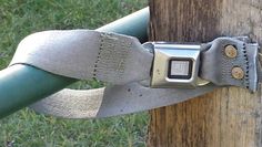 a close up of a metal object attached to a wooden pole with grass in the background