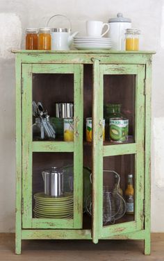 a green cabinet with dishes and cups on it