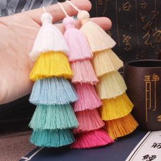 three tassels in different colors are being held by a person's hand