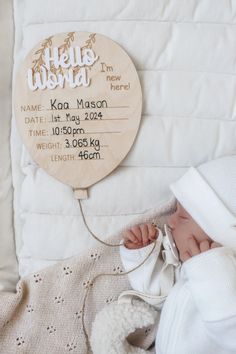 a baby is sleeping next to a wooden sign