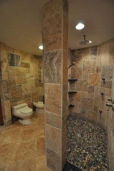 a bathroom with stone walls and flooring in the shower area, toilet on the far side