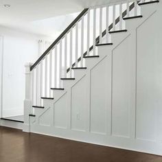 an empty room with white walls and black railings on the stair case, next to a wooden floor