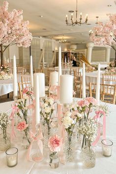 there are many vases with flowers and candles on the table