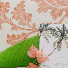 the wedding stationery is decorated with pink flowers and palm tree leaves, along with an envelope