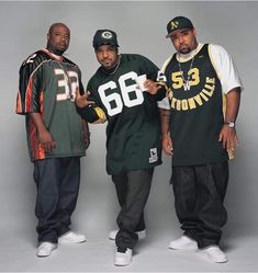 three men standing next to each other in front of a gray background wearing green and yellow jerseys