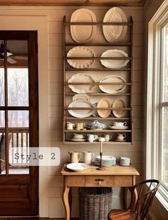 a wooden table topped with plates next to a wall mounted shelf filled with cups and saucers