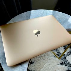 an apple laptop sitting on top of a glass table