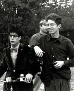 black and white photograph of three men on bicycles with one holding a drink in his hand