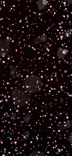 pink and blue speckles are falling from the dark sky on a black background