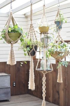 several hanging planters with plants in them on a porch next to a chest of drawers