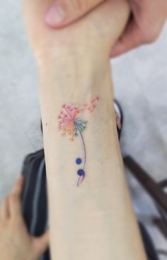 a woman's arm with a flower tattoo on the left side of her wrist