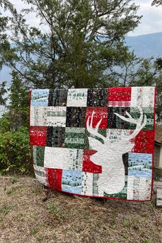 a quilt made to look like a deer is on display in front of some trees