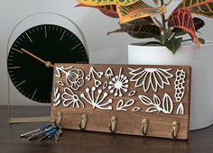 a wooden clock and some keys are on a table next to a potted plant