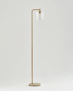 a floor lamp with a clear glass shade on the top and a gold metal base