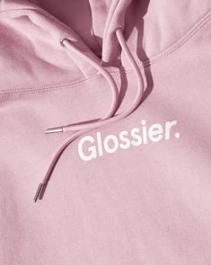 a close up of a pink hoodie with the word glossier printed on it