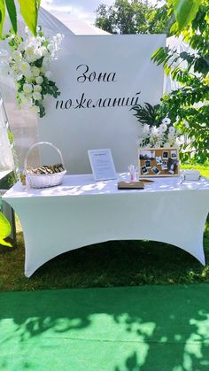 the table is set up for an event with white flowers and greenery on it