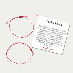 two red string bracelets sitting next to each other on top of a white card