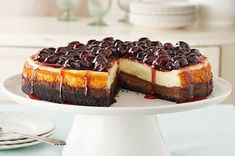 a cheesecake with chocolate and cherry toppings on a cake platter, ready to be eaten