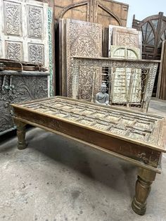 an old wooden table with ornate carvings on the top and sides, surrounded by other antique furniture