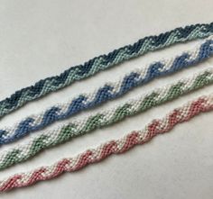 three braided bracelets sitting next to each other on top of a white table