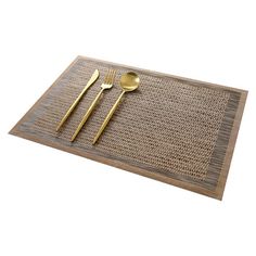 a place mat with two gold spoons and a fork on it next to a pair of golden utensils