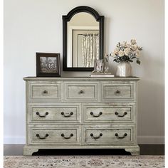 an old dresser with flowers and a mirror on top