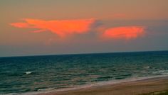 an orange cloud hangs over the ocean at sunset