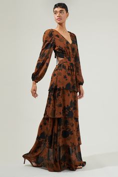 You and the Sandy Floral Pleated Maxi Dress are going to be an unstoppable pair! This long dress features a deep v-neckline followed by long sleeves with elastic cuffs. It has tiered layers on the bottom skirt that overlay to give it an extra touch. The back cut out and design is got to be our favorite detail. This dress can be easily be paired up with any type of boots, heels or flats! - V-neck- Ruffle layers- Back cut out - Balloon long sleeves- Color: Brown BlackSize + Fit - Model is 5'8" and Print Chiffon Dress, Open Back Maxi Dress, Baltic Born, Tiered Maxi Skirt, Got To Be, Brown Background, Chiffon Material, Pleated Maxi Dress, Pleated Maxi