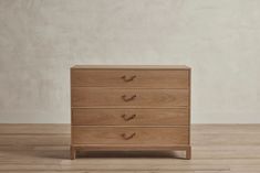 a wooden dresser sitting on top of a hard wood floor next to a white wall