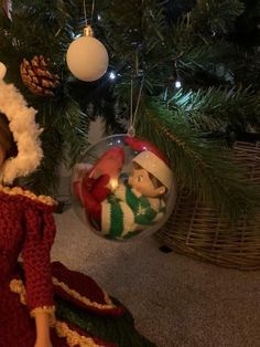 a christmas ornament with an elf and snowman on it next to a christmas tree