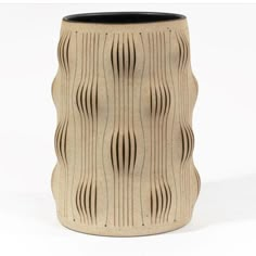 a ceramic vase with wavy lines on the outside and black inside, sitting in front of a white background