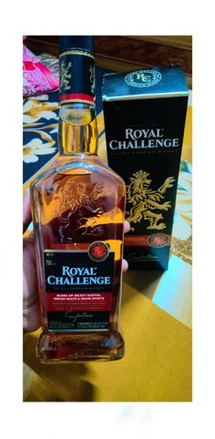 a bottle of royal challenge sitting on top of a table next to a box of liquor