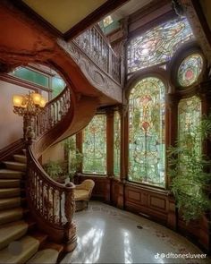 an ornate staircase with stained glass windows and wooden railings, along with potted plants