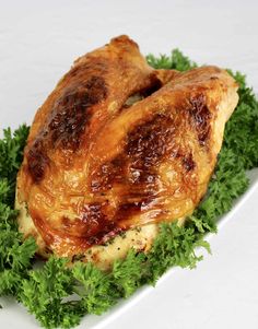 a whole chicken is sitting on top of some green leafy garnished greens