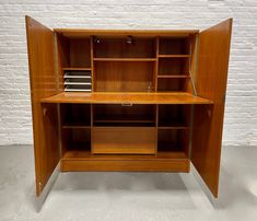 a wooden desk with shelves and drawers in front of a white brick wall or floor