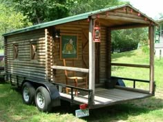 a small log cabin sitting on top of a trailer in the middle of a field